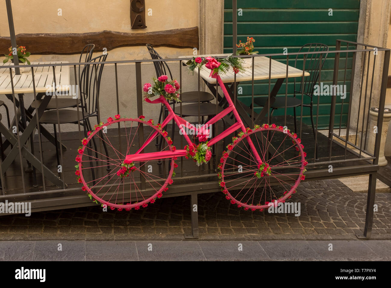 Eine altmodische Zyklus, lackiert rosa und lehnte sich gegen das Geländer der ein Restaurant und mit dem Rahmen und Räder von Blumen und Bändern geschmückt Stockfoto