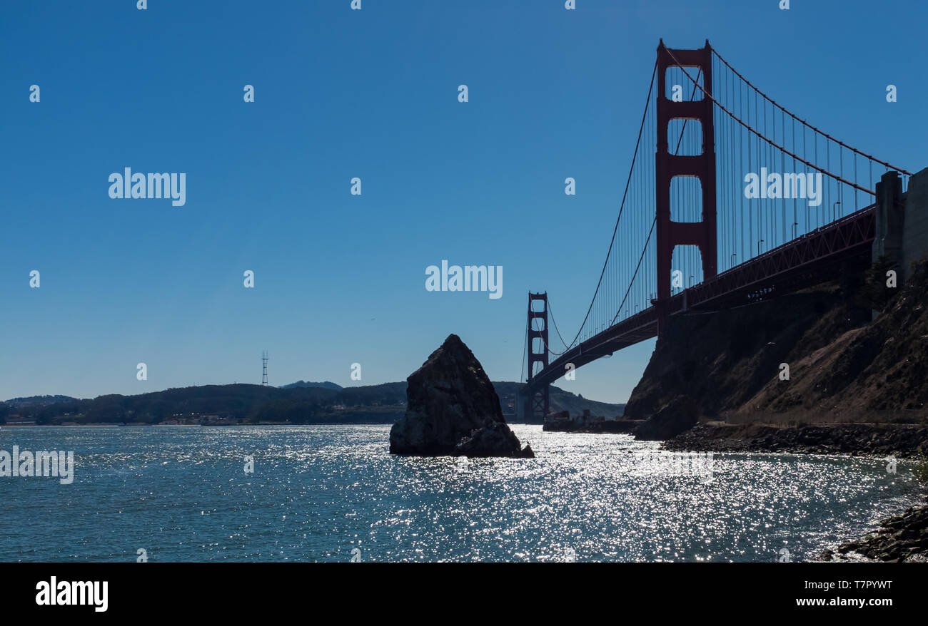 Ein niedriger Betrachtungswinkel und der atemberaubenden berühmten Golden Gate Bridge vom malerischen Baker Beach gegen einen strahlend blauen Himmel an einem sonnigen Tag gesehen, San Francisco, Kalifornien, USA Stockfoto