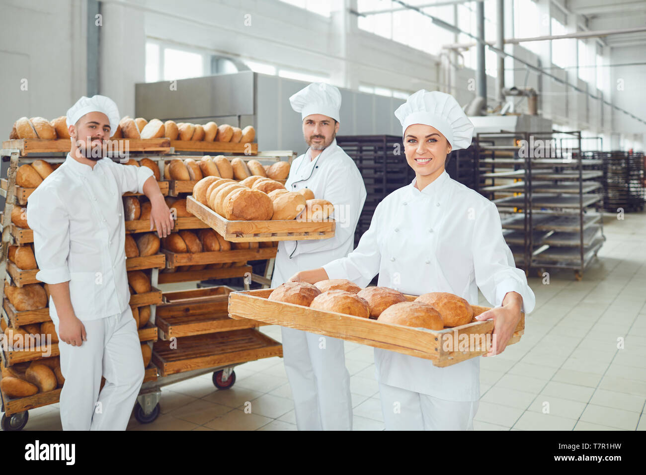 Bäcker halten Sie ein Tablett mit frischem Brot in der Bäckerei. Stockfoto