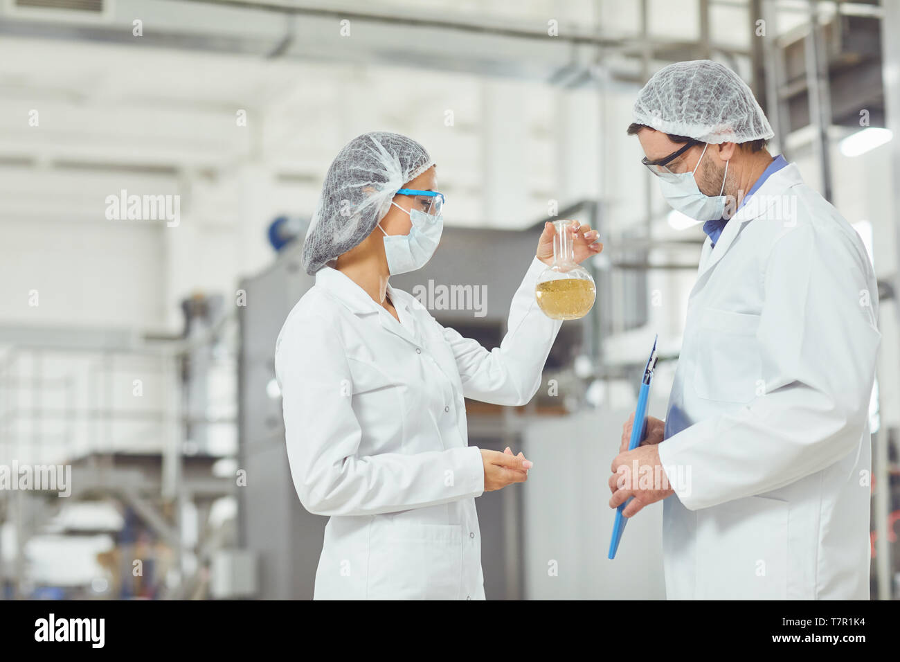 Technologe in Masken und Mäntel Blick in die Flüssigkeit Stockfoto