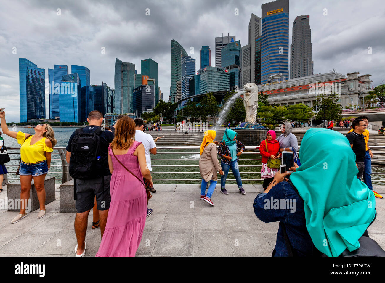 Touristen posieren für Fotos Vor dem Merlion Statue und die Skyline von Singapur, Singapur, Südostasien Stockfoto