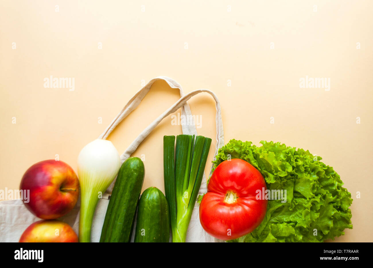 Frisches Obst und Gemüse im eco Beutel auf beige Farbe Hintergrund mit Copyspace. Kunststoff Konzept. Stockfoto