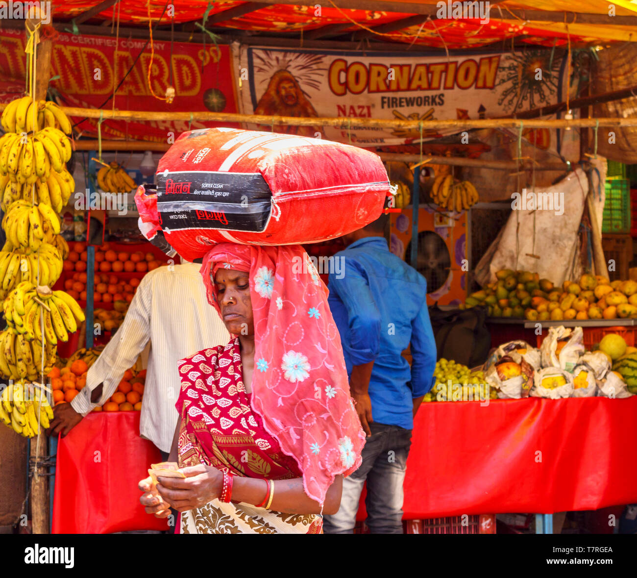 Straßenszene in Shahpura, ein dindori Kreisstadt in Madhya Pradesh, Indien: Ein lokaler alte Frau zählt Geld, die ein Paket auf dem Kopf Stockfoto