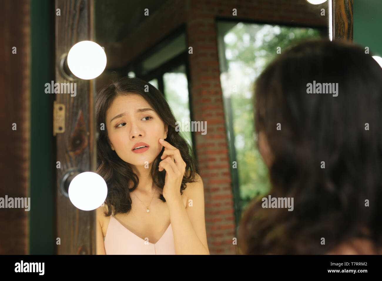 Reflexion im Spiegel. Frau schaut in den Spiegel, bemerken die ersten Fältchen Stockfoto