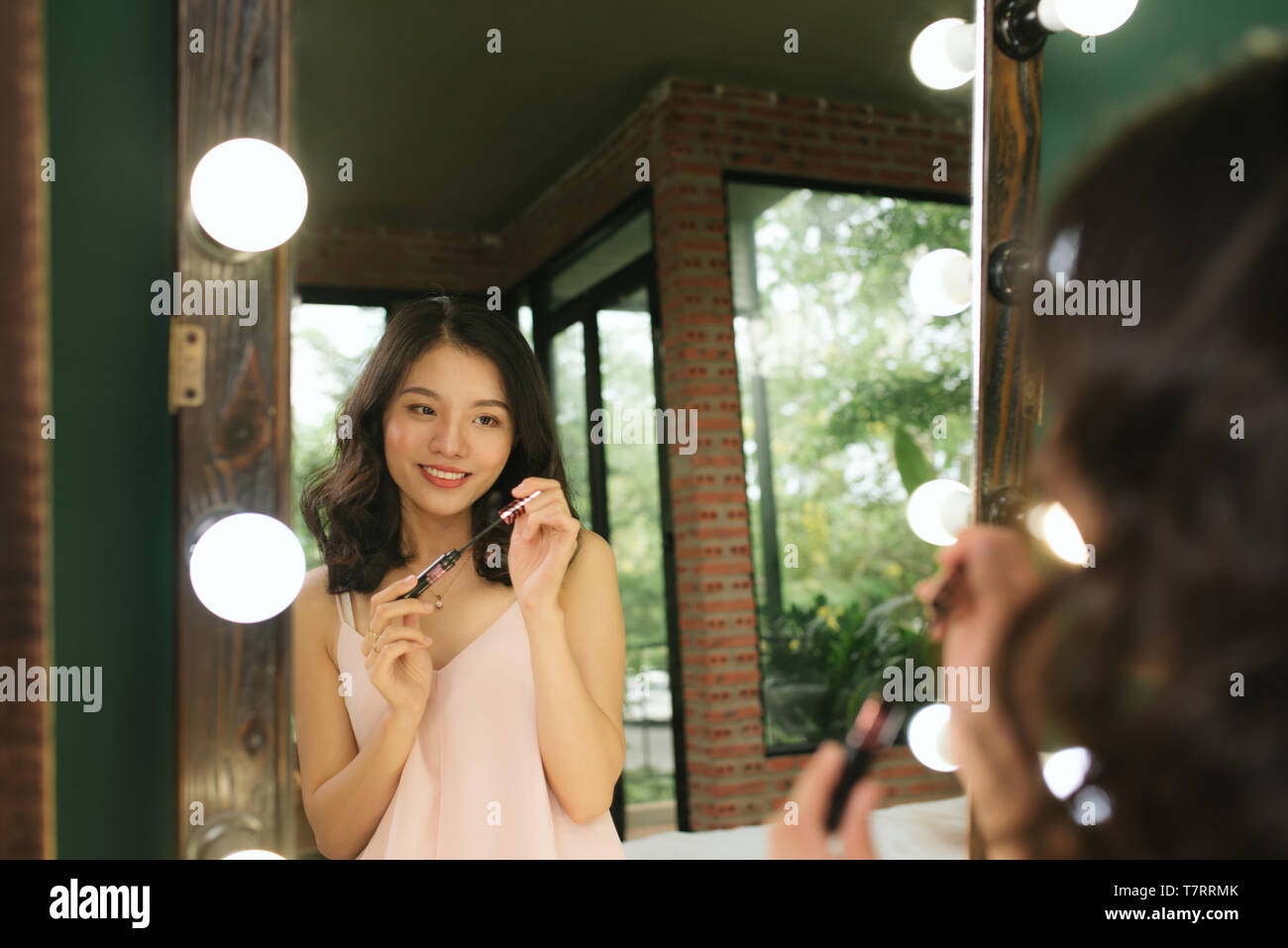 Vietnamesische Mädchen mascara Anwendung vor großer Spiegel Stockfoto