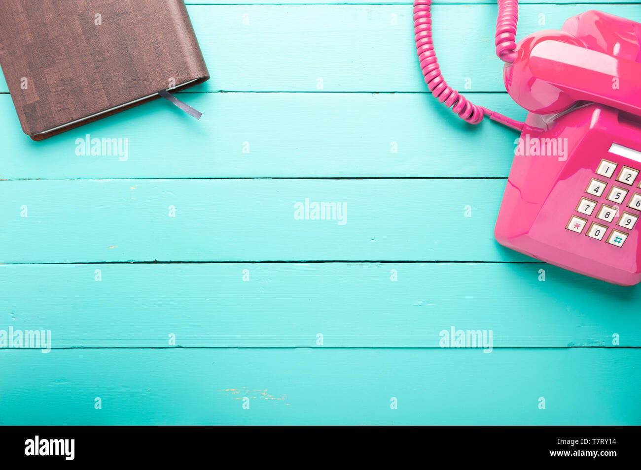 Classic rosa Telefon Empfänger mit Notebook, wartenden Anruf, Retro Telefon und Buch auf alten grünen Holzboden. Stockfoto