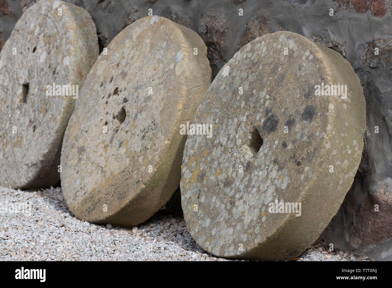 Drei Mühlsteine stützte, gegen eine Mauer aus Stein Stockfoto