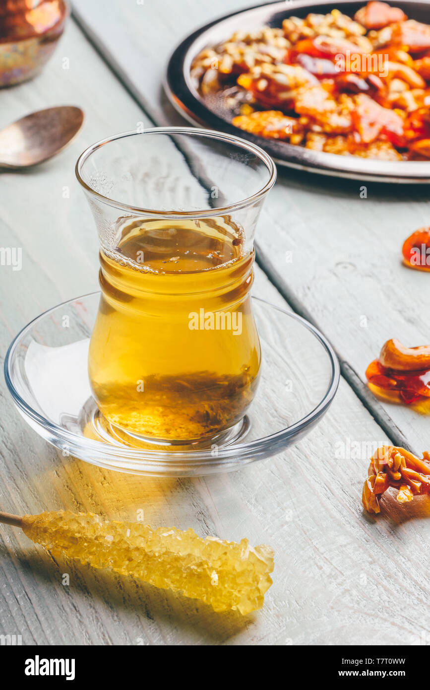 Kräutertee in armudu Glas mit arabischen Köstlichkeiten auf Metallplatte über Licht Holz- Oberfläche Stockfoto