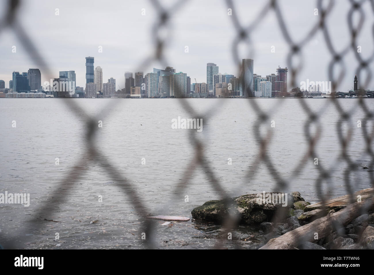 Manhattan Skyline Blick durch einen Zaun entlang dem Hudson River Greenway in New York durch einen blauen Himmel Frühjahr Stockfoto