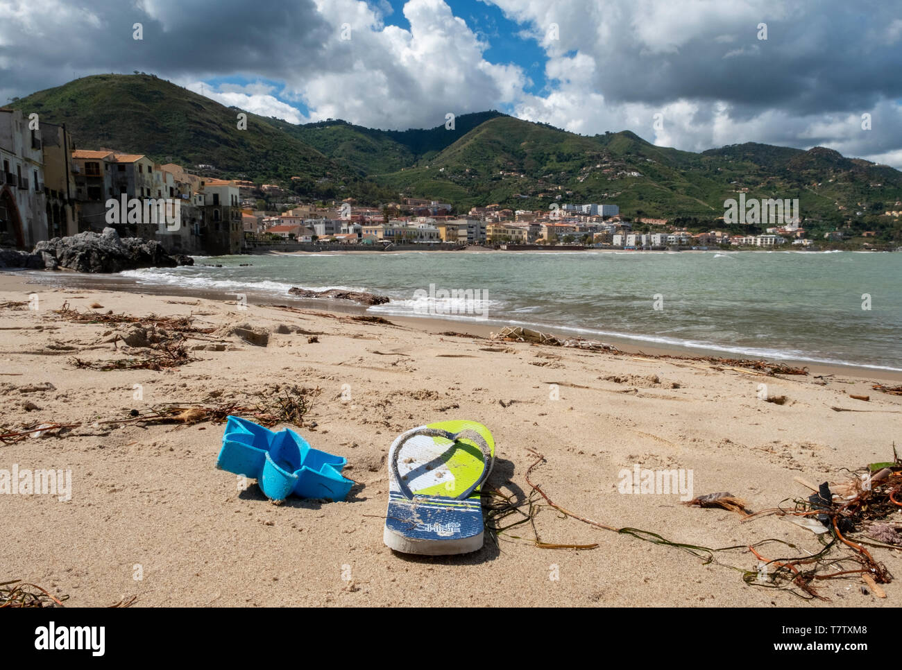 Flip Flop und angeschwemmte Seegras am Strand von Cefalù, Sizilien. Stockfoto