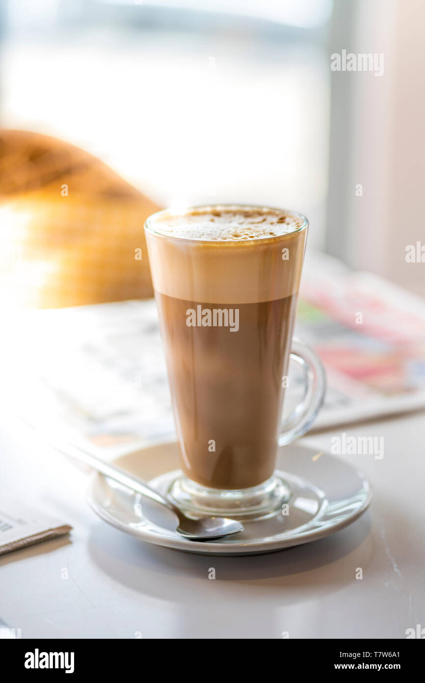 Ein Glas Latte Kaffee neben einer Tageszeitung. Latte ist mit Espresso und gedämpfte Milch und stammt aus Italien. Stockfoto