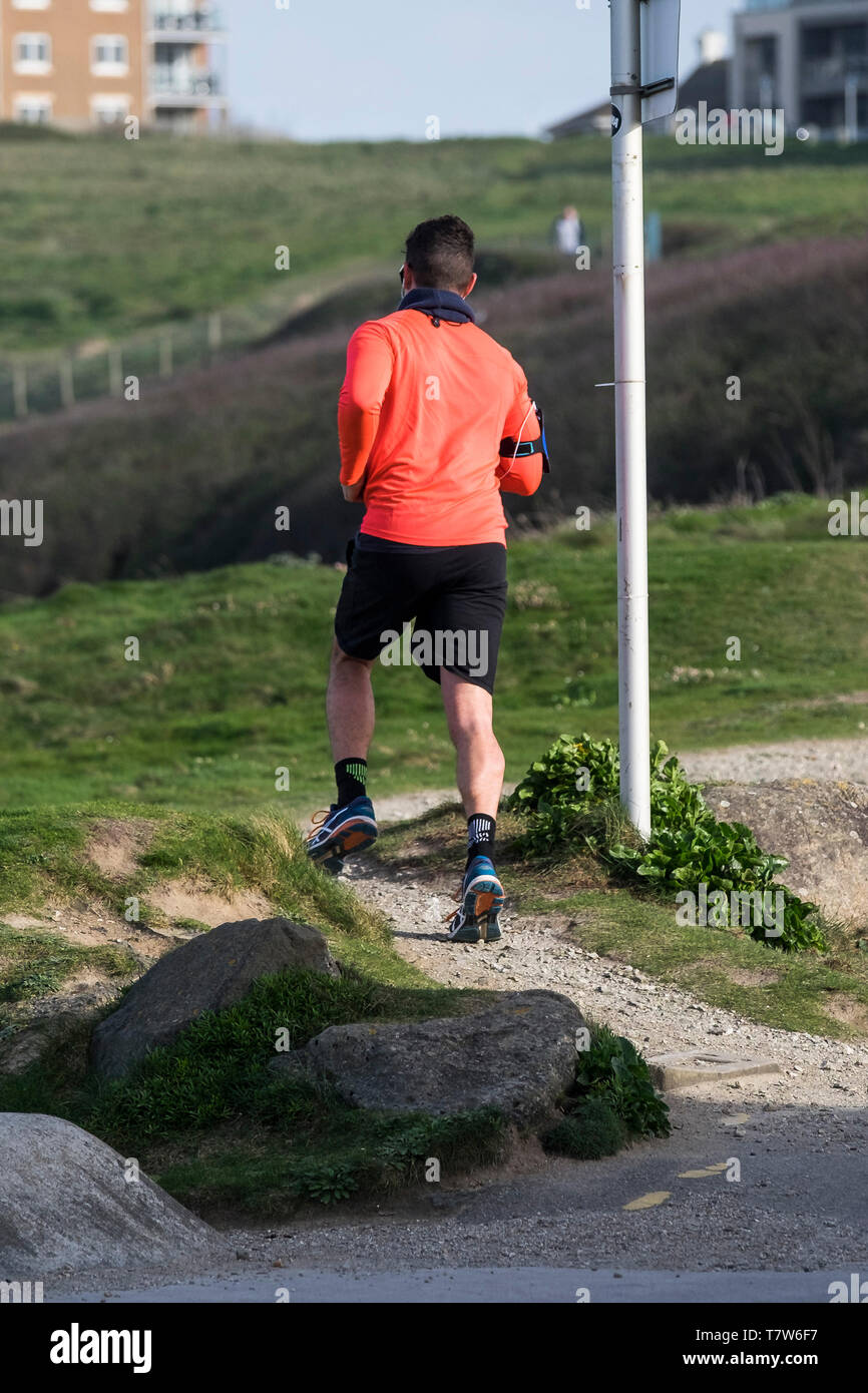 Ein Läufer joggen auf einem küstenweg auf den Towan Kopf in Newquay in Cornwall. Stockfoto
