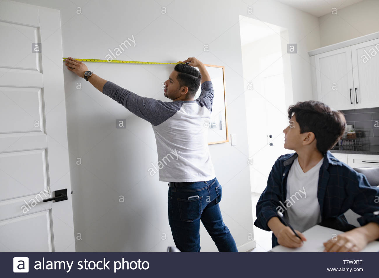 Vater und Sohn messen Wand mit Maßband für DIY-Projekt Stockfoto