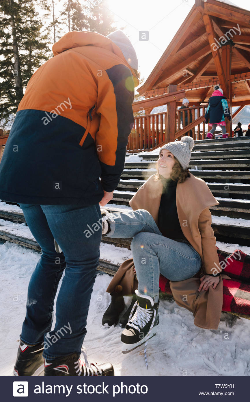 Freund binden's Freundin Schlittschuh auf verschneiten Schritte Stockfoto