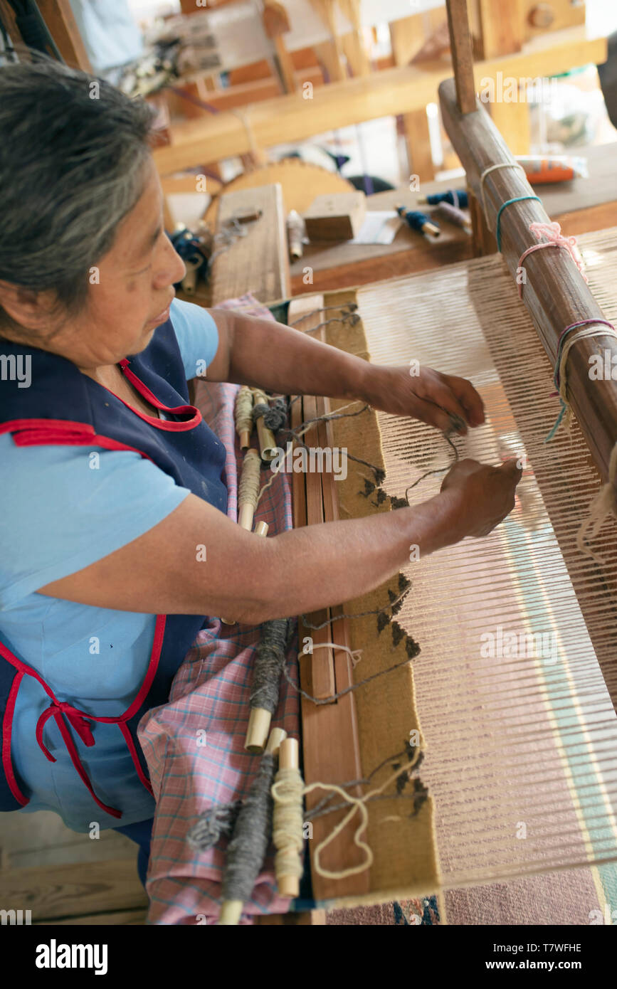Zapotec Frau weben eine Wolldecke auf ein Pedal Webstuhl. Teotitlan del Valle, Oaxaca, Mexiko. Apr 2019 Stockfoto