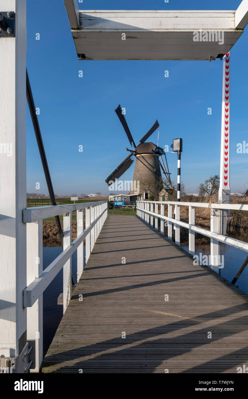 Blue Sky holländische Landschaft mit der Mühle über die weiße Brücke über einem ruhigen und klaren Wasser am frühen Morgen, Niederlande Stockfoto