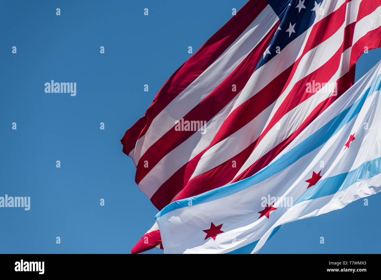 Die kommunalen Flagge von Chicago und die amerikanische Flagge im Wind weht in Chicago gegen blauen Himmel Stockfoto