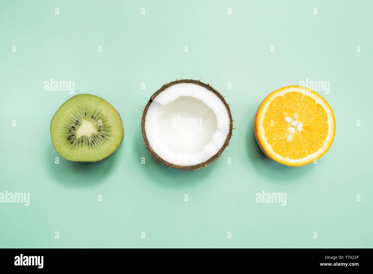 Kiwi, Kokosnuss und orange auf grünem Hintergrund. Konzept der fruitarianism, Vegetarismus, Veganismus, natürliche Vitamine und Gesundheit. Stockfoto