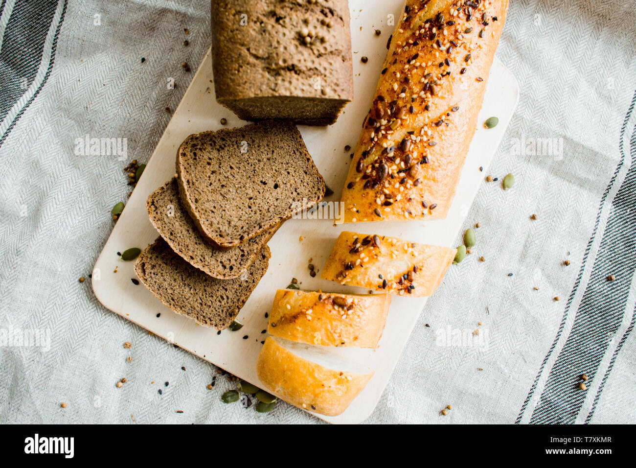 Frisch gebackene geschnittenes Brot auf einem Holzbrett auf dunkelgrau Stoff mit Saatgut Stockfoto
