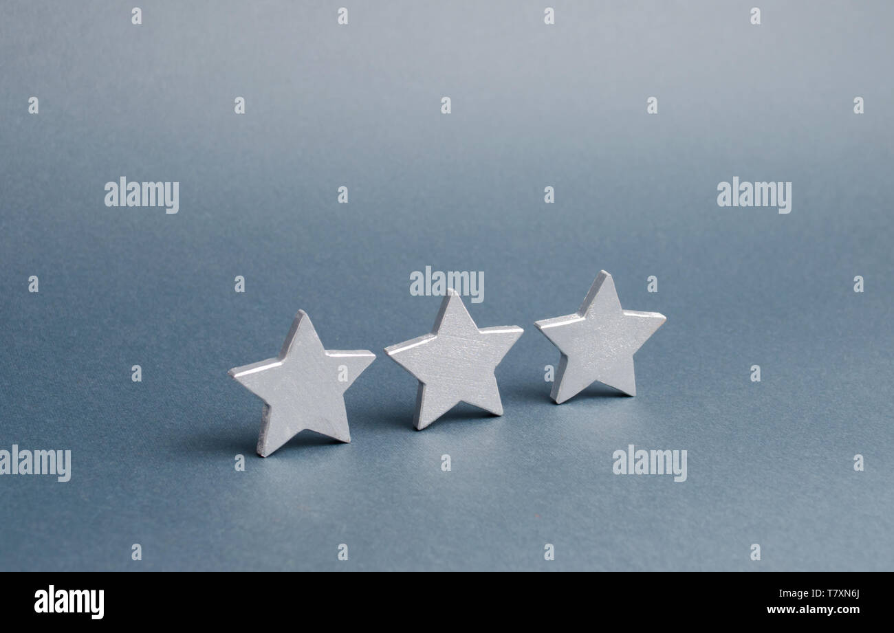 Drei Sterne auf einem grauen Hintergrund. Das Konzept der Bewertung und Evaluierung. Die Bewertung der Hotel-, Restaurant-, mobile Anwendung. Qualität, Service, buye Stockfoto