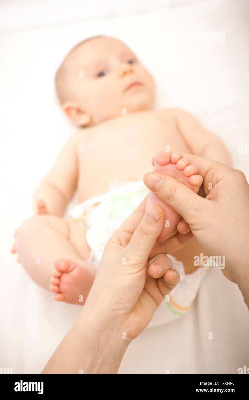 Porträt eines Neugeborenen, die eine Fußmassage gegeben ist. Konzept der Pflege und Gesundheit des Kindes. Stockfoto