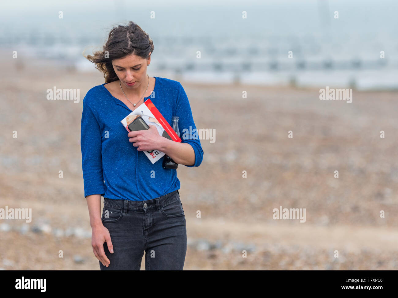Junge Frau allein spazieren, beim Denken an einem Strand im Frühling. Einsame Frau alleine zu Fuß unterwegs. Zeit Konzept zu denken. Einsamkeit Konzept. Stockfoto