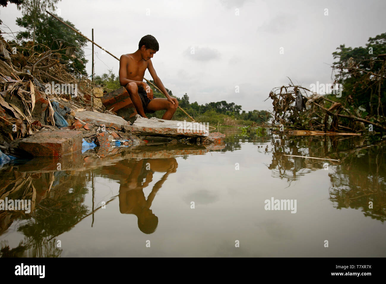 Mohammad Khokon sitzt neben Was verwendet das Haus seiner Familie zu sein. Eine grelle Flut gewaschen in den Yamuna Fluss in Sirajganj, Bangladesch im Jahr 2007. Die globale Erwärmung verursachen der Monsun Regen und Überschwemmungen früher zu starten. Die globale Erwärmung auch accellerate das Schmelzen von Eis und Schnee im Himalaya, die Feeds in den bereits gesättigten Flüsse, der Ganges Delta machen. Das Resultat ist verheerend für Menschen, die in den dicht besiedelten delta Bereich leben. Während der Himalaya und Überschwemmungen aus dem Norden wreak Verwüstung, der Anstieg des Meeresspiegels Salzwasser eindringen in die geringe Ursache liegenden landwirtschaftlichen Zonen entlang. Stockfoto