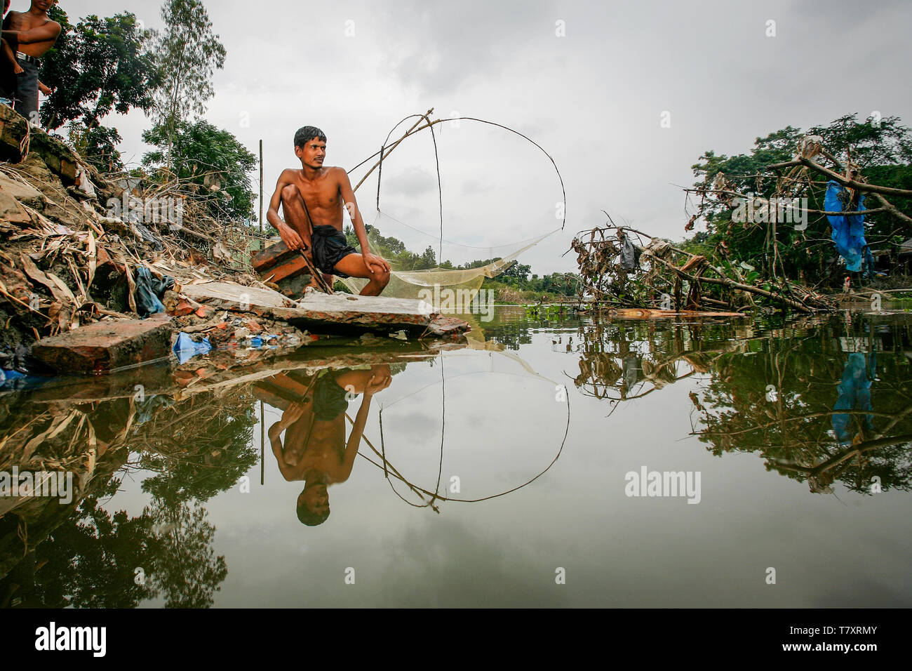 Mohammad Khokon sitzt neben Was verwendet das Haus seiner Familie zu sein. Eine grelle Flut gewaschen in den Yamuna Fluss in Sirajganj, Bangladesch im Jahr 2007. Die globale Erwärmung verursachen der Monsun Regen und Überschwemmungen früher zu starten. Die globale Erwärmung auch accellerate das Schmelzen von Eis und Schnee im Himalaya, die Feeds in den bereits gesättigten Flüsse, der Ganges Delta machen. Das Resultat ist verheerend für Menschen, die in den dicht besiedelten delta Bereich leben. Während der Himalaya und Überschwemmungen aus dem Norden wreak Verwüstung, der Anstieg des Meeresspiegels Salzwasser eindringen in die geringe Ursache liegenden landwirtschaftlichen Zonen entlang. Stockfoto