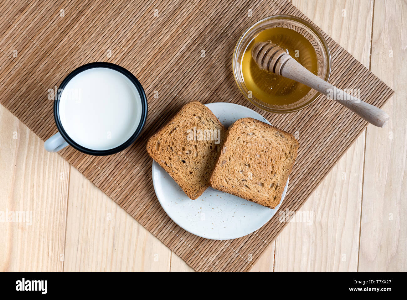 Zwei Scheiben Toast mit Zinn Becher Milch und Krug Honig auf einer hölzernen Table Setup Stockfoto