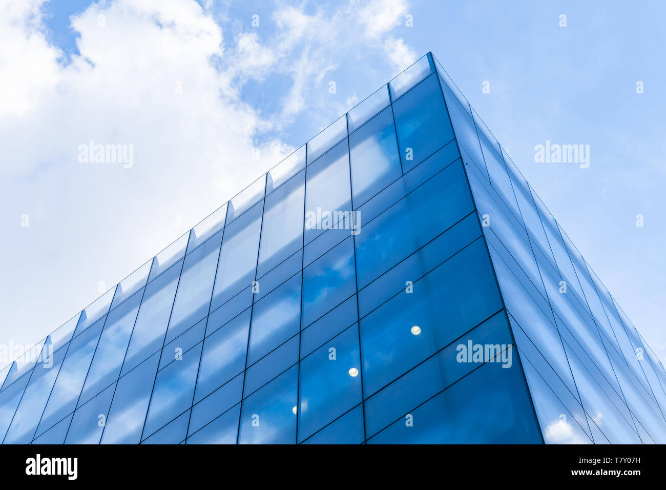 Abstrakte moderne Architektur Fragment, Ecke von Wänden aus glänzendem Glas und Stahl unter blauen bewölkten Himmel Stockfoto