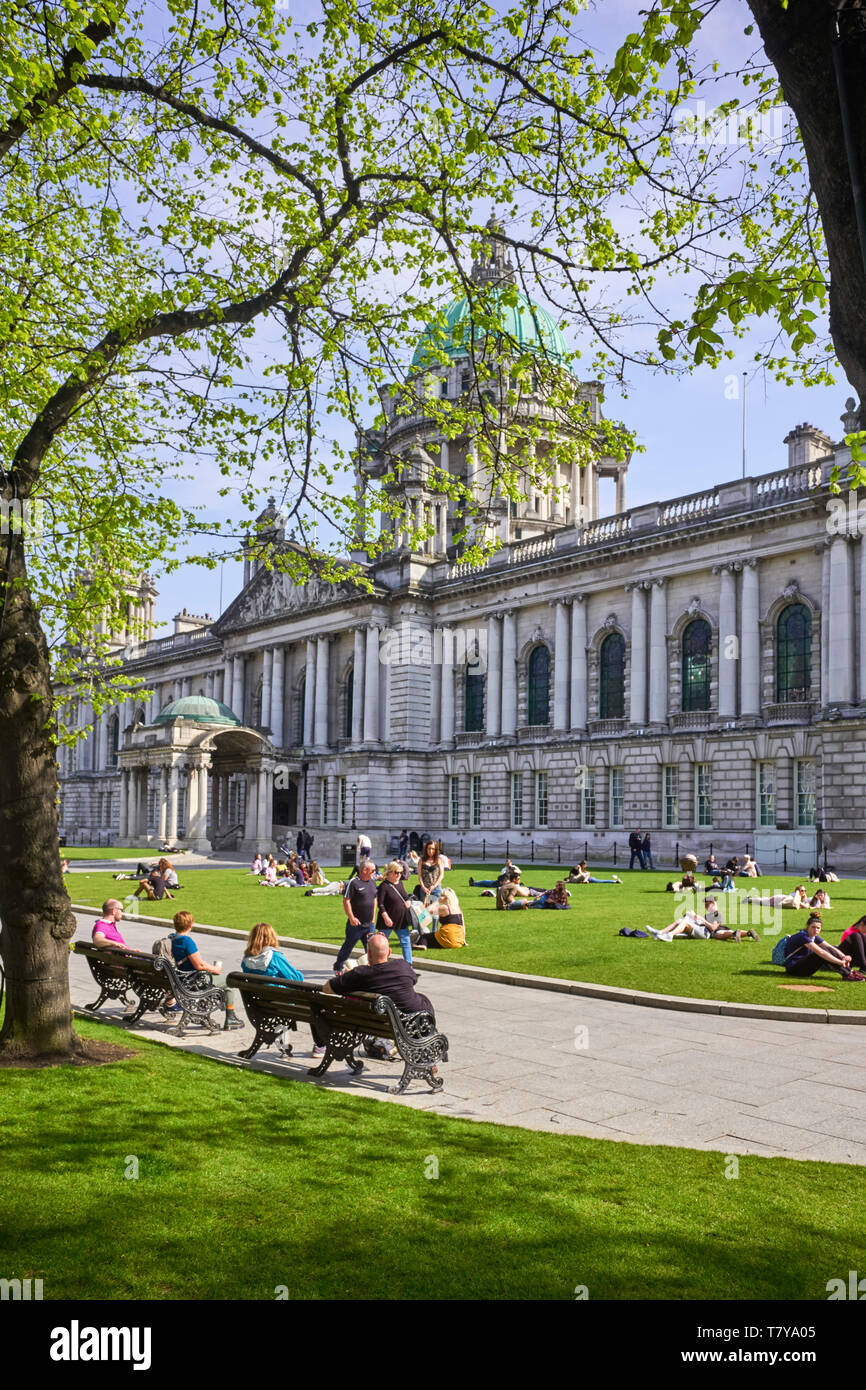 Sonnenanbeter auf dem Gras außerhalb Belfast City Hall Stockfoto