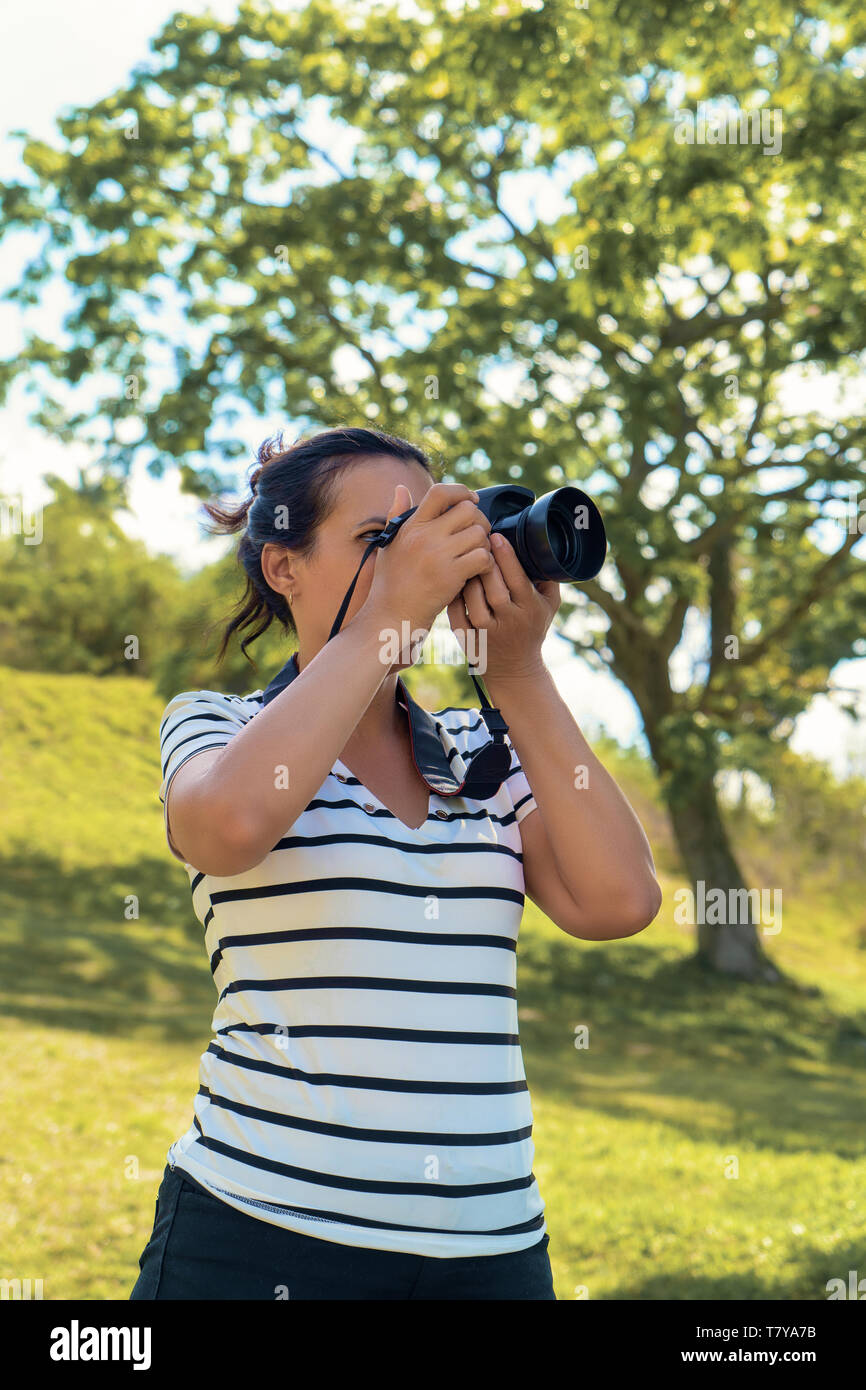 Ein schwarzes Haar stand eine Frau mit Kamera Aufnehmen von Bildern Stockfoto