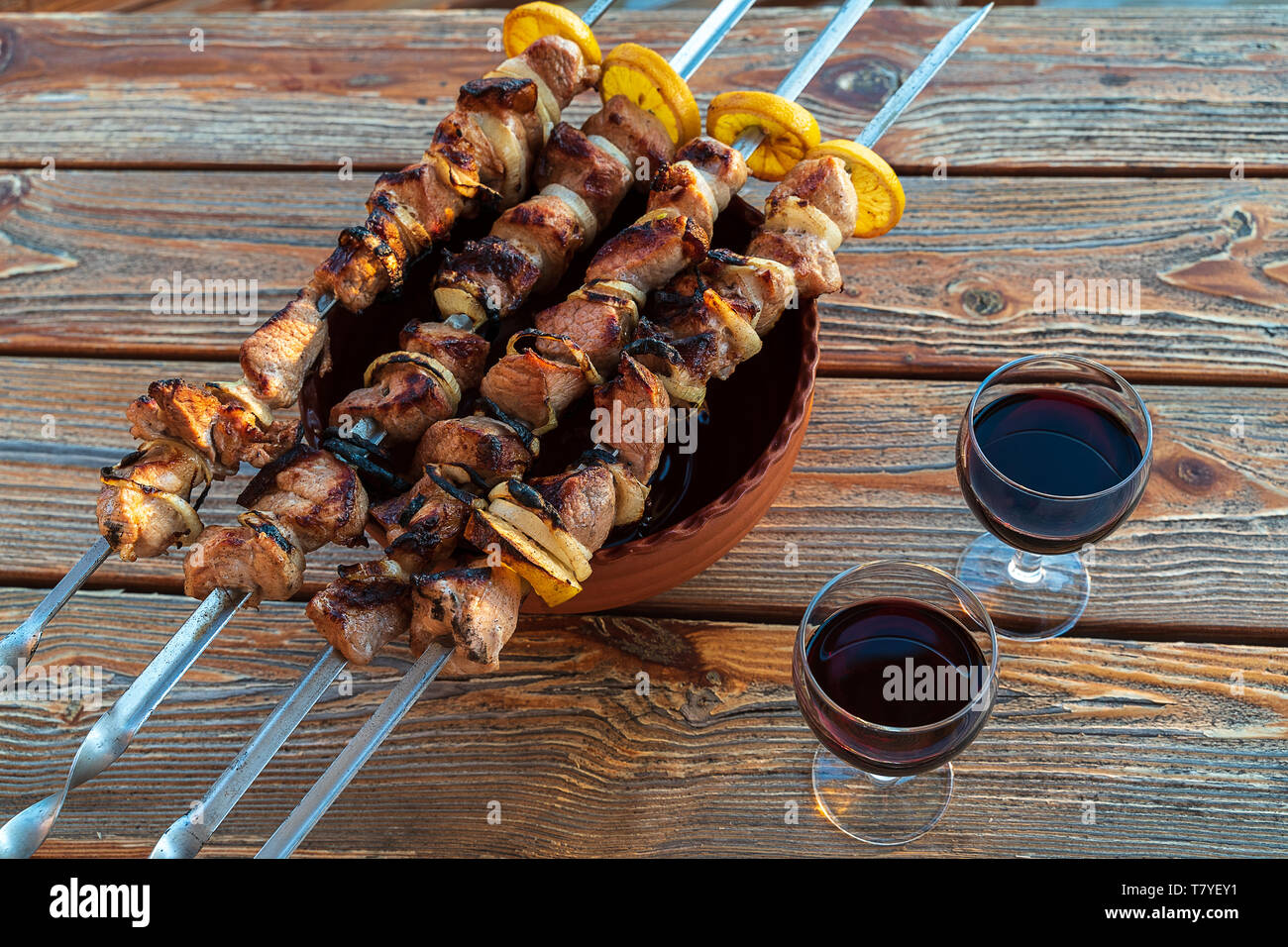 Hot Schweinefleisch Grillen am Grill mit Gewürzen und Gläser Rotwein zubereitet, auf hölzernen Tisch. Stockfoto