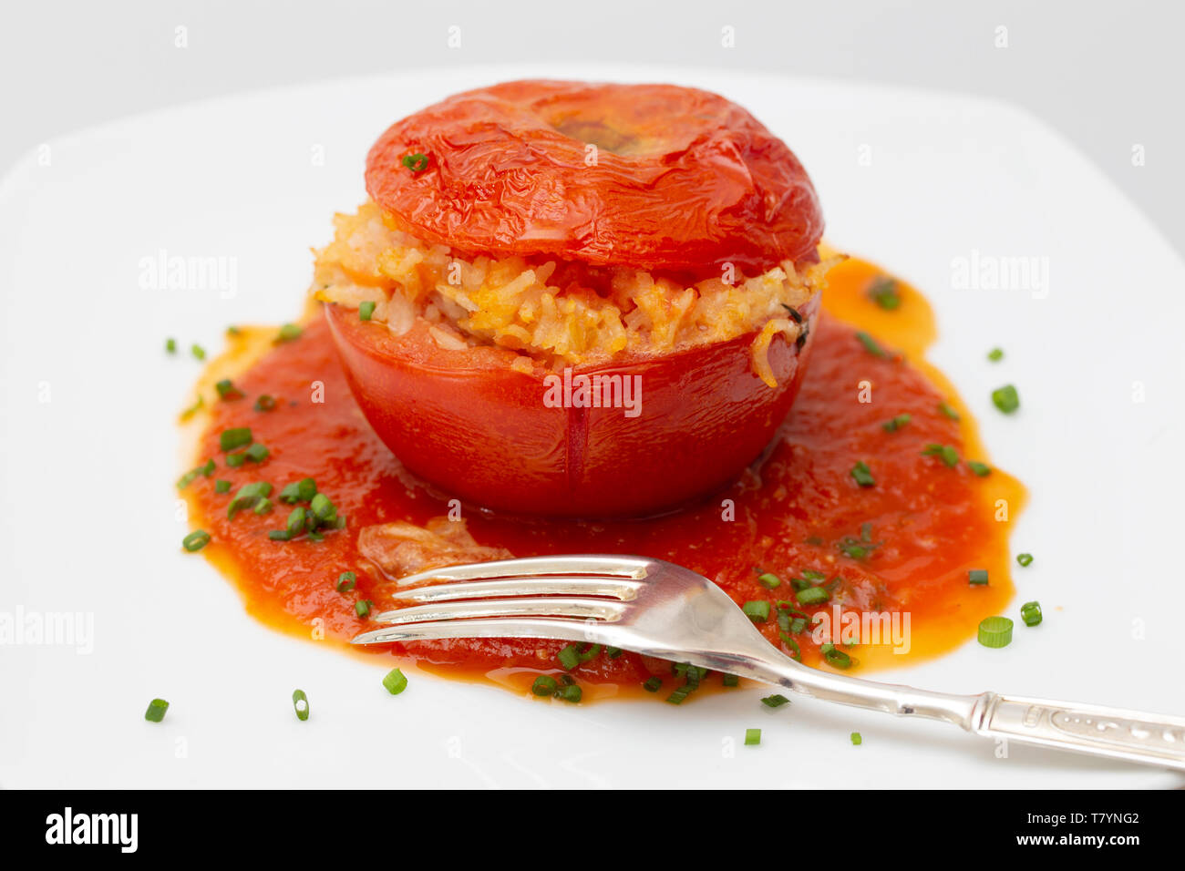 Gefüllte Tomaten garniert mit gehackten Schnittlauch auf einem Teller mit der Gabel Stockfoto