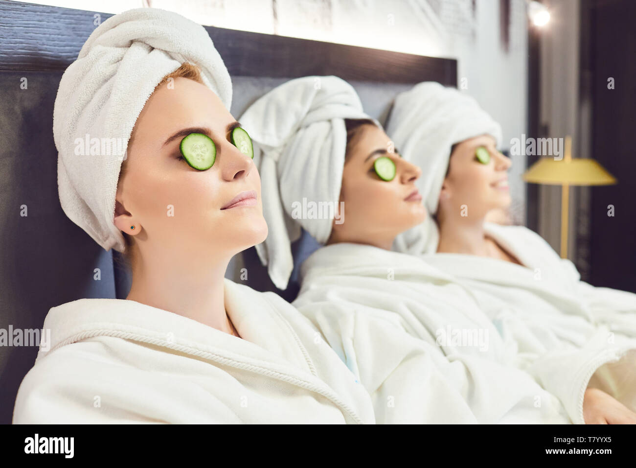 Kuehlung Frauen in Bademäntel mit Gurkenscheiben auf dem Gesicht Stockfoto
