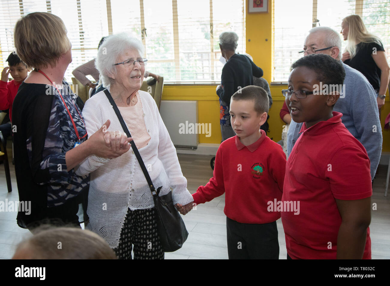 Schule Kinder besuchen eine Pflege zu Hause Singen und Tanzen mit den Kunden, von denen einige ältere Menschen sind, und einige haben Demenz. Stockfoto