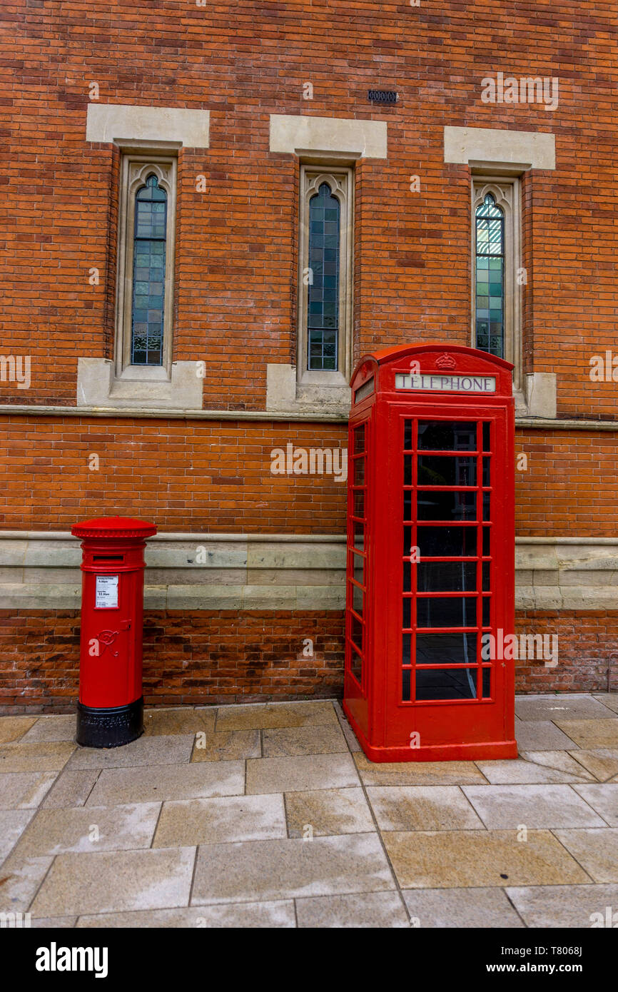 Rotes Telefon Kiosk und roten Briefkasten neben einander vor einem Backsteingebäude. Stockfoto