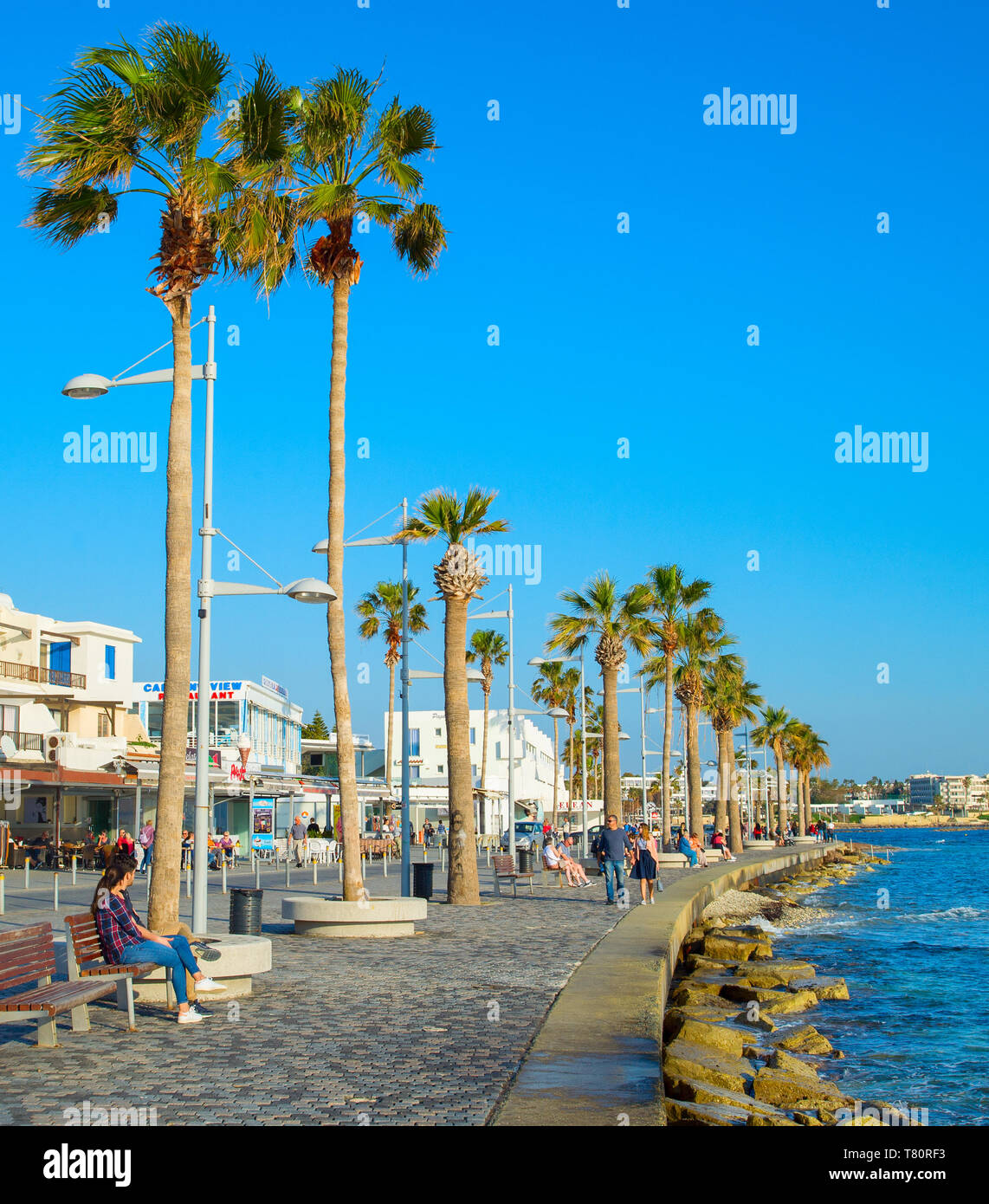 PAPHOS, Zypern - 13. FEBRUAR 2019: Menschen auf Paphos Promenade bei Sonnenuntergang. Paphos ist die berühmte touristische Destination in Zypern Stockfoto