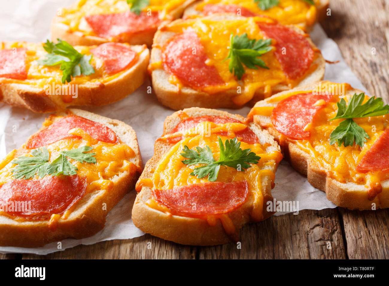 Köstliche Vorspeisen Toast mit Salami Wurst und geschmolzene Cheddar Käse close-up auf dem Tisch. Horizontale Stockfoto
