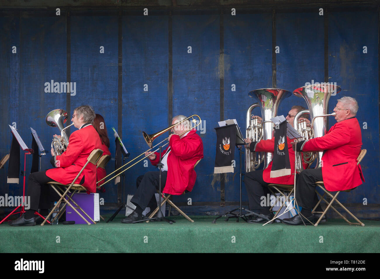 Die Musiker aus dem Phoenix Brass Band in roten Jacken spielen auf der Bühne auf Ihre umgebauten Sattelschlepper Anhänger. Stockfoto
