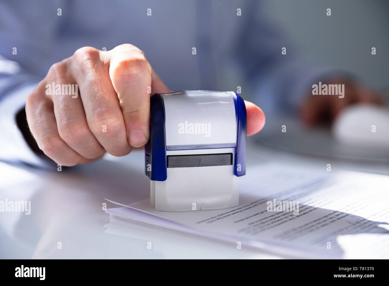 Nahaufnahme von einer Person Hand Stanzen mit Genehmigt Stempel auf Dokument am Schreibtisch Stockfoto