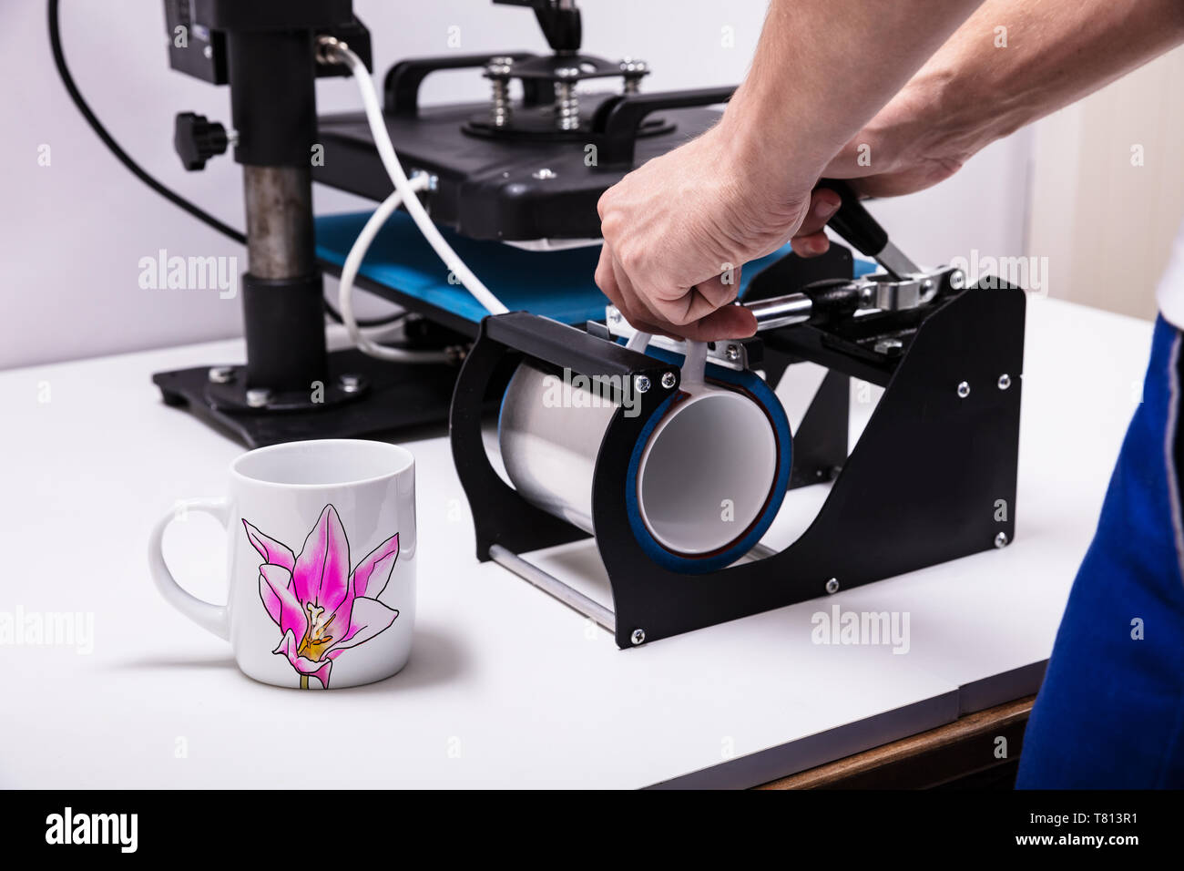 Man Druck auf Kaffeetassen in Werkstatt Stockfoto