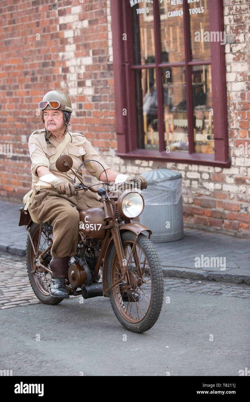 Senior man, in Armeeuniform als Militär-Versandfahrer, isoliert im Freien mit Oldtimer-Motorrad, Motorrad, Black Country Museum vierziger Jahre WW2-Veranstaltung. Stockfoto