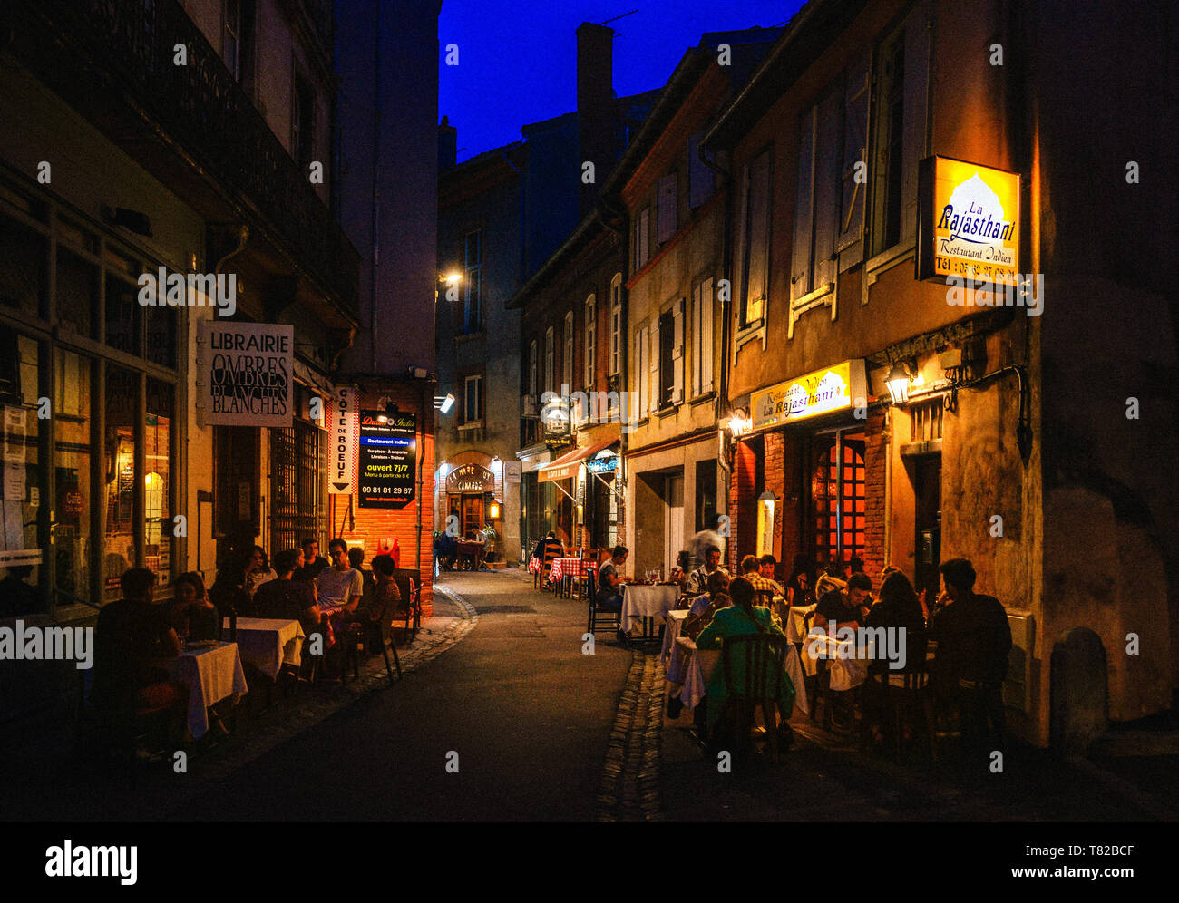 Eine typische Gasse in den Französischen Occitanie Stadt Toulouse in der Dämmerung, mit Menschen Essen in Restaurants. Stockfoto