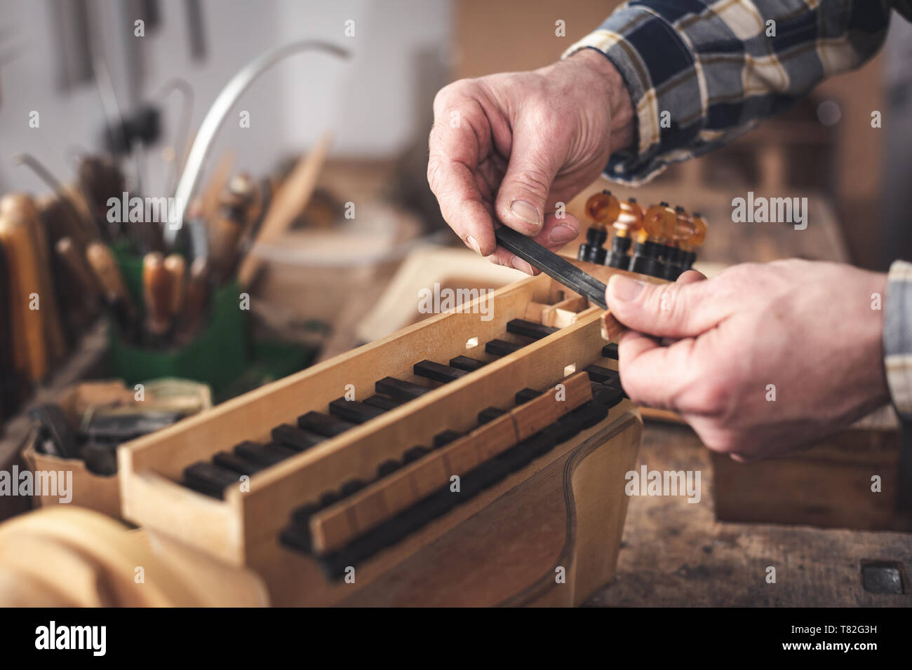 Instrumentenbauer der einen Schlüssel einer Drehleier in seinen Händen Stockfoto