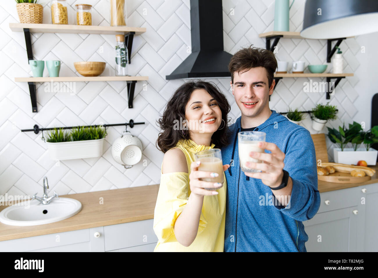 Glückliches junges Paar essen Saft in Ihre Küche. Ein netter Kerl und ein Mädchen Saft trinken aus Gläsern und lächelnd Stockfoto