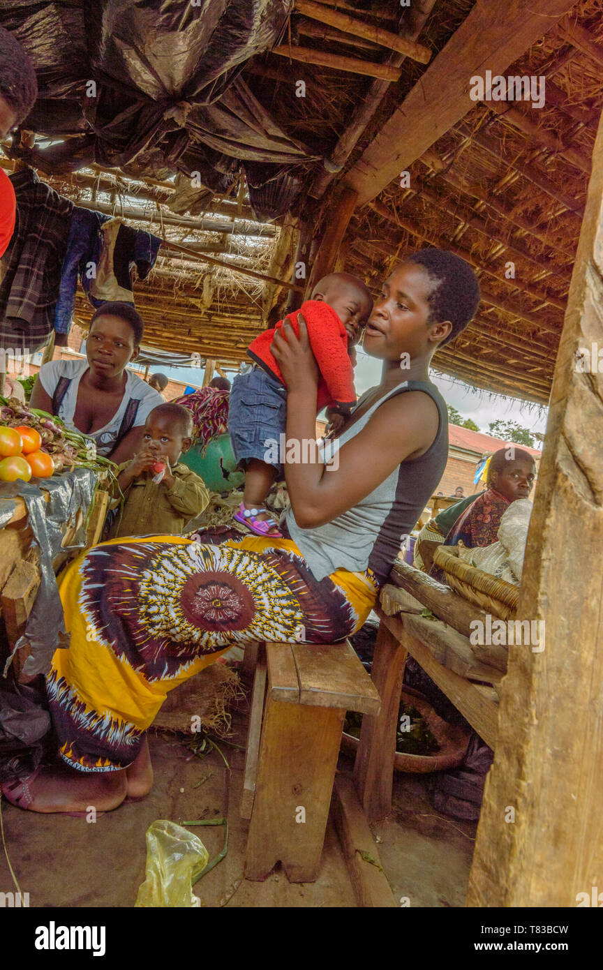 Malawische Frau hält ihren kleinen Sohn auf einer Bank am Markt verkaufen Gemüse Dedza Malawi Stockfoto