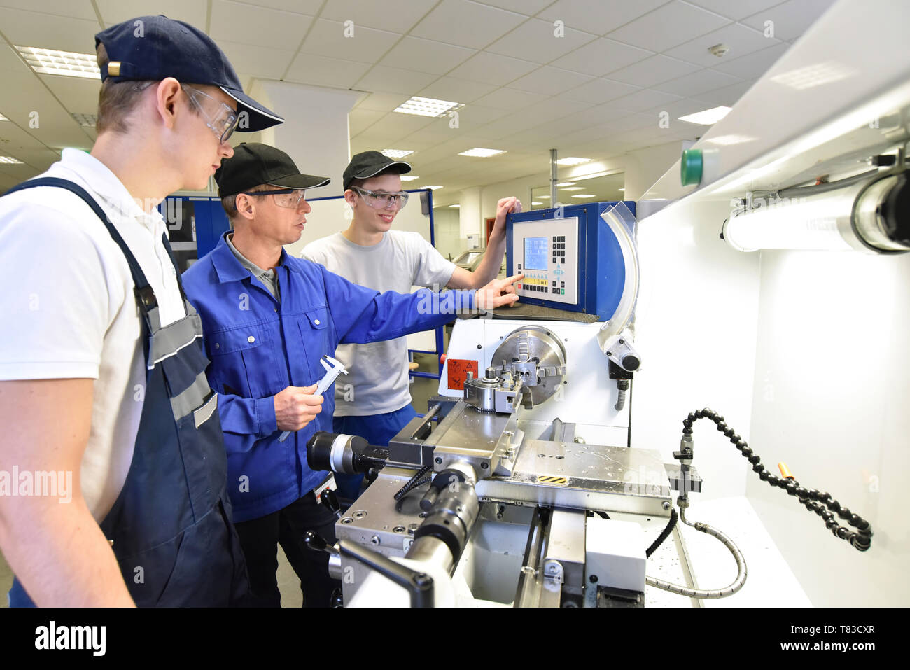 Junge Auszubildende in der Technischen Berufsbildung werden von älteren Ausbilder auf CNC-Drehmaschinen Maschine unterrichtet Stockfoto