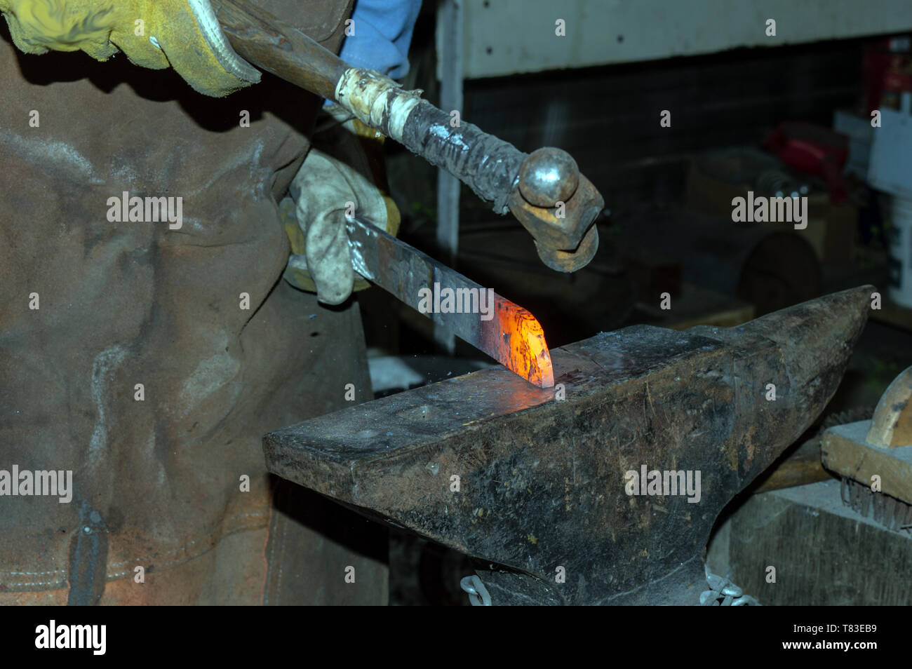 Die professionellen Schmied Formen der Punkt eines Messers, während das Metall rot glühenden heiß ist. Bokeh Hintergrund. Stockfoto