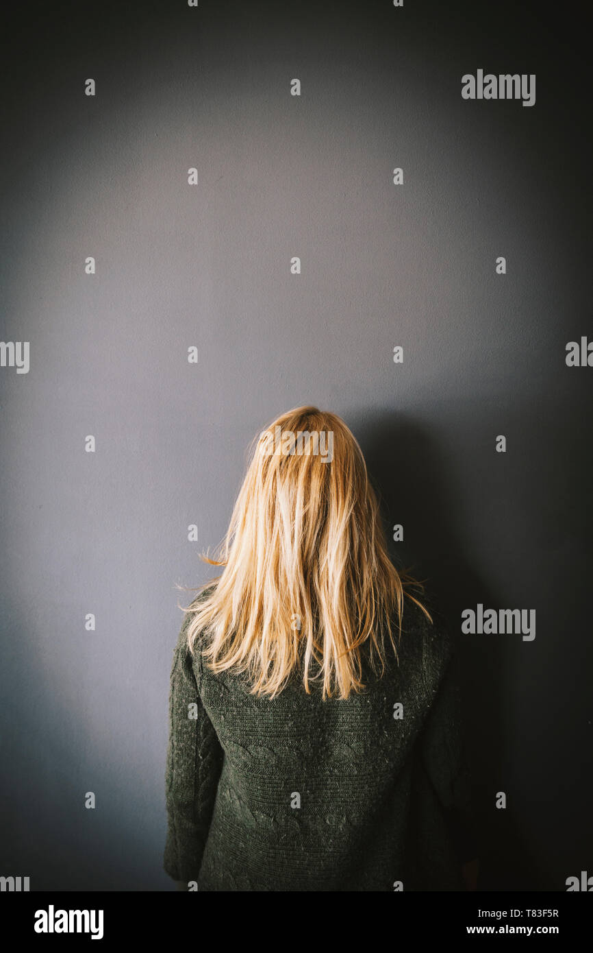 Frau mit blonden Haaren wandte sich an der Wand suchen. Kopieren Sie Platz Stockfoto